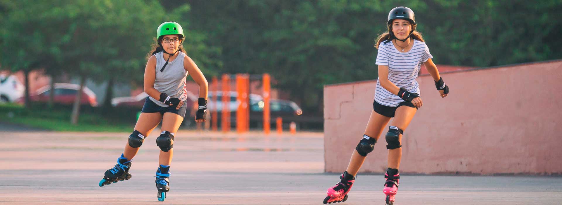 Two young girls wearing protective equipment and Powerslide inline kids skates roll toward the camera