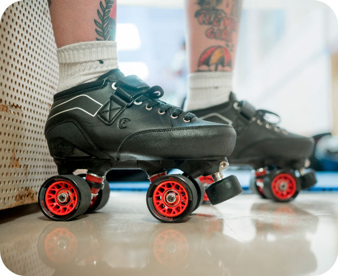 A close-up image of a person with tattoos on their legs wearing Chaya Jade roller skates