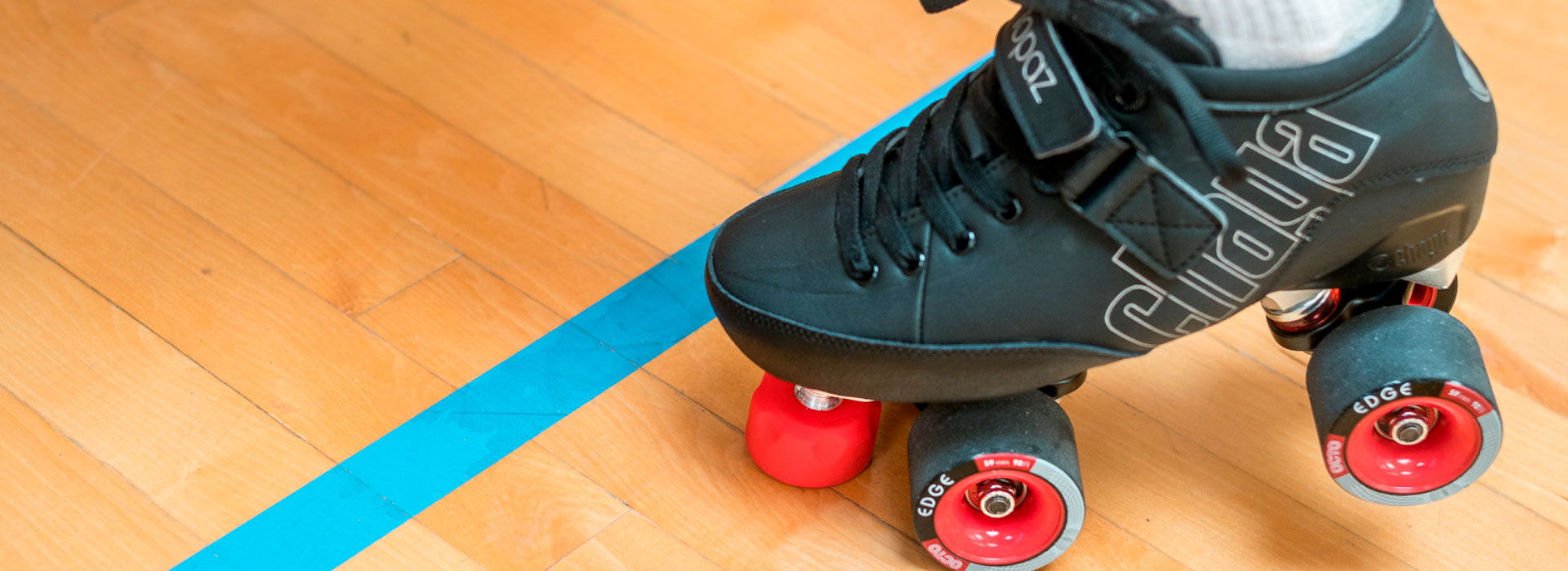 Bottom half of a roller derby skater with a single hand touching the ground