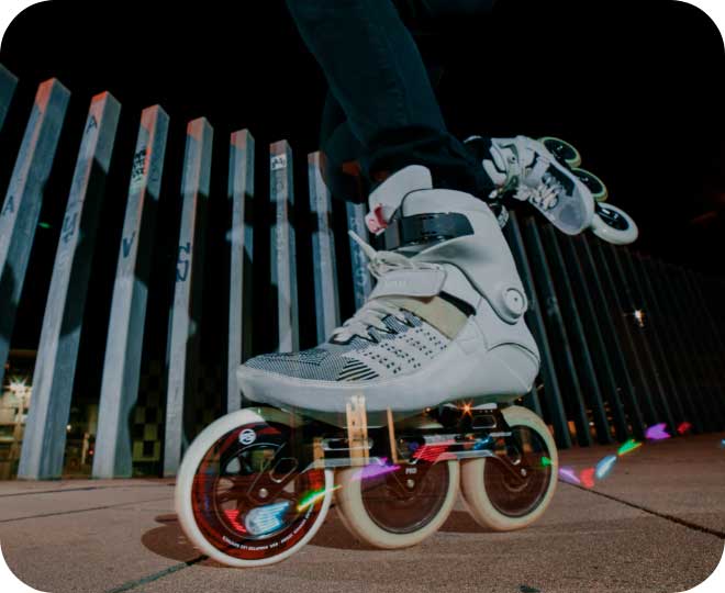 A close-up image of a person skating at night with Graphix wheels illuminating