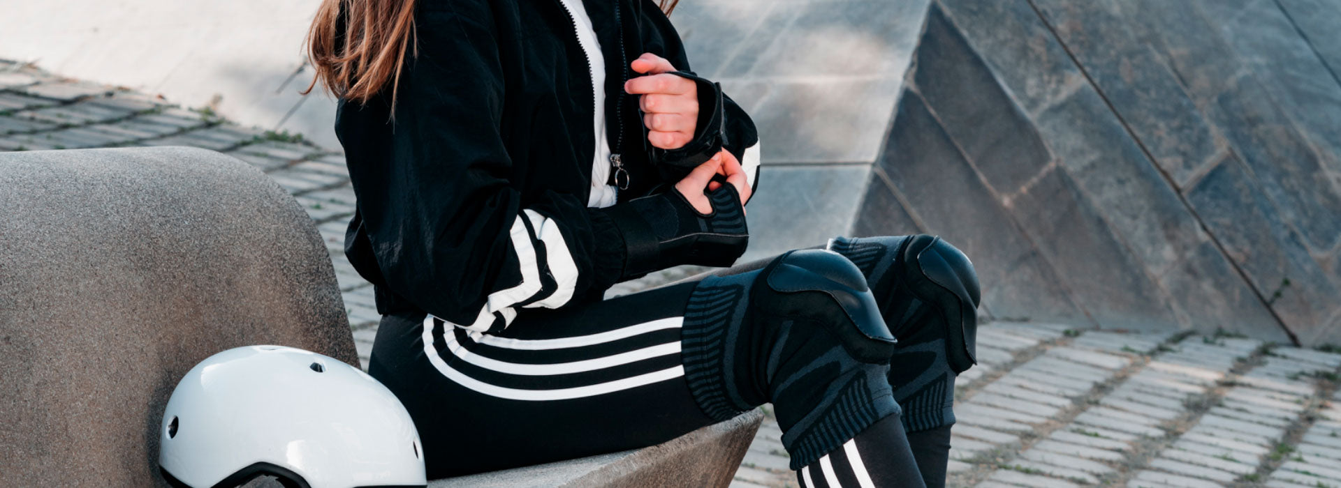 A close-up image of a woman sitting on stairs and wearing Powerslide protective gear